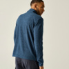 Person von hinten in blauer Fleecejacke und dunkler Hose, schaut über die rechte Schulter, heller Hintergrund