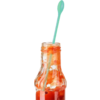 Bouteille en verre avec une sauce rouge et un mélangeur en plastique vert dans la bouteille