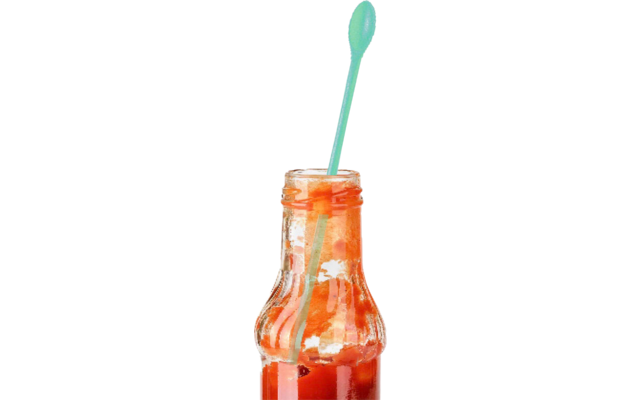 Bouteille en verre avec une sauce rouge et un mélangeur en plastique vert dans la bouteille