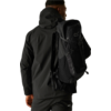 Person in schwarzer Outdoorjacke und schwarzem Rucksack, Rückenansicht