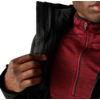 Hand hält den Reißverschluss einer schwarzen Jacke, darunter ein rotes, gestreiftes Shirt