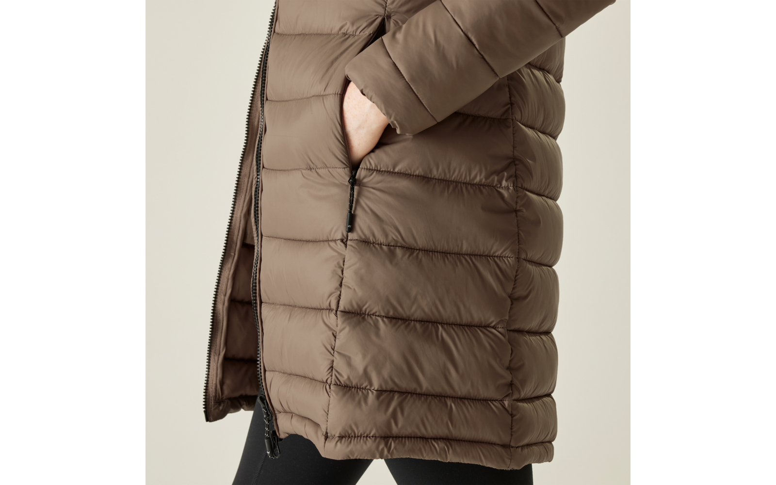 Braune Steppjacke mit Taschen, darüber eine Hand in der Tasche steckend