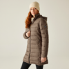 Frau mit rotem Haar trägt eine beige Mütze und eine lange braune Steppjacke