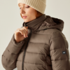 Frau in brauner Winterjacke und beige Mütze blickt nach unten
