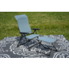 Fauteuil pliant bleu clair avec structure métallique noire et repose-pieds assorti sur un tapis gris à motif floral blanc sur de l'herbe