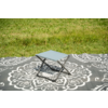 Petit tabouret pliant avec assise bleu clair sur une couverture à motif gris et blanc sur l'herbe