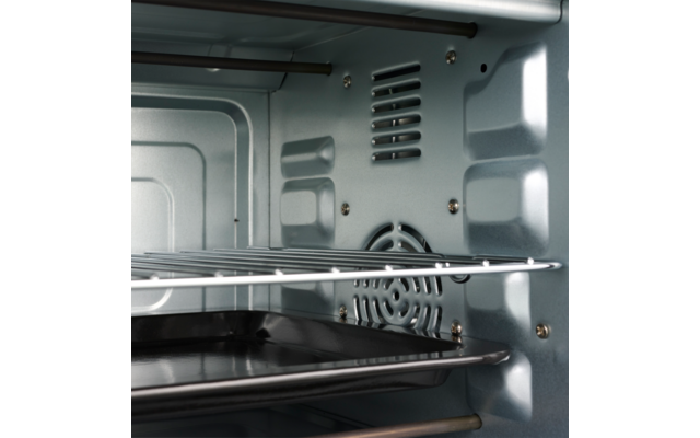 Metalen binnenkant van een oven met twee draadroosters, een bakplaat en een ronde ventilatierooster op de achterwand