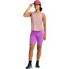 Person mit rosa Basecap, ärmellosem rosa Oberteil, hellvioletten Radshorts, schwarzen Socken und grauen Sportschuhen; stehend, eine Hand an der Cap-Krempe