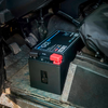 Schwarze Autobatterie in Fahrzeuginnenraum mit roten und blauen Kabelanschlüssen