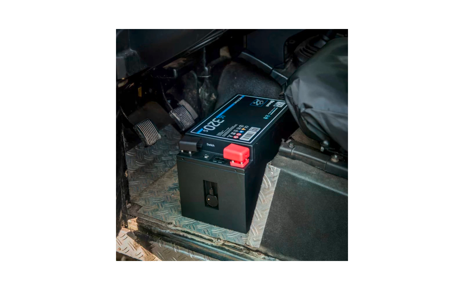 Schwarze Autobatterie in Fahrzeuginnenraum mit roten und blauen Kabelanschlüssen