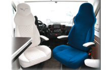 Two vehicle seats, one white and one blue, with armrests inside a vehicle interior