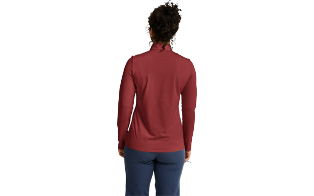 Persona vista de espaldas con prenda de manga larga roja y pantalones azules, cabello rizado oscuro recogido en un moño