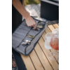 Main prenant des couverts dans une pochette grise en tissu sur une table en bois