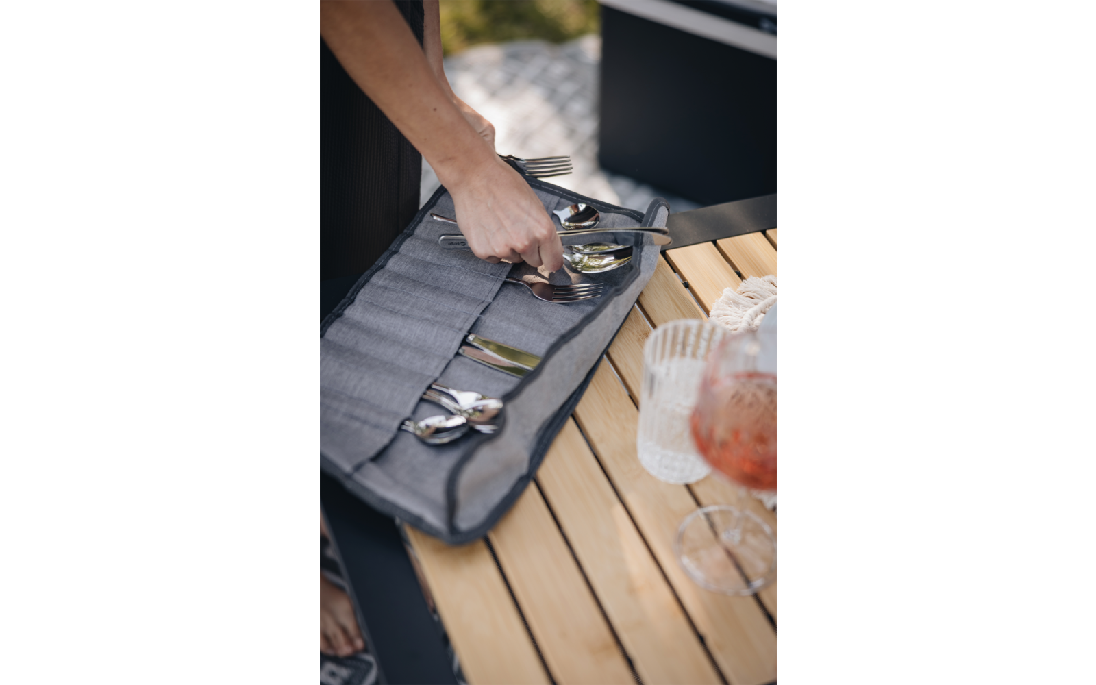 Main prenant des couverts dans une pochette grise en tissu sur une table en bois