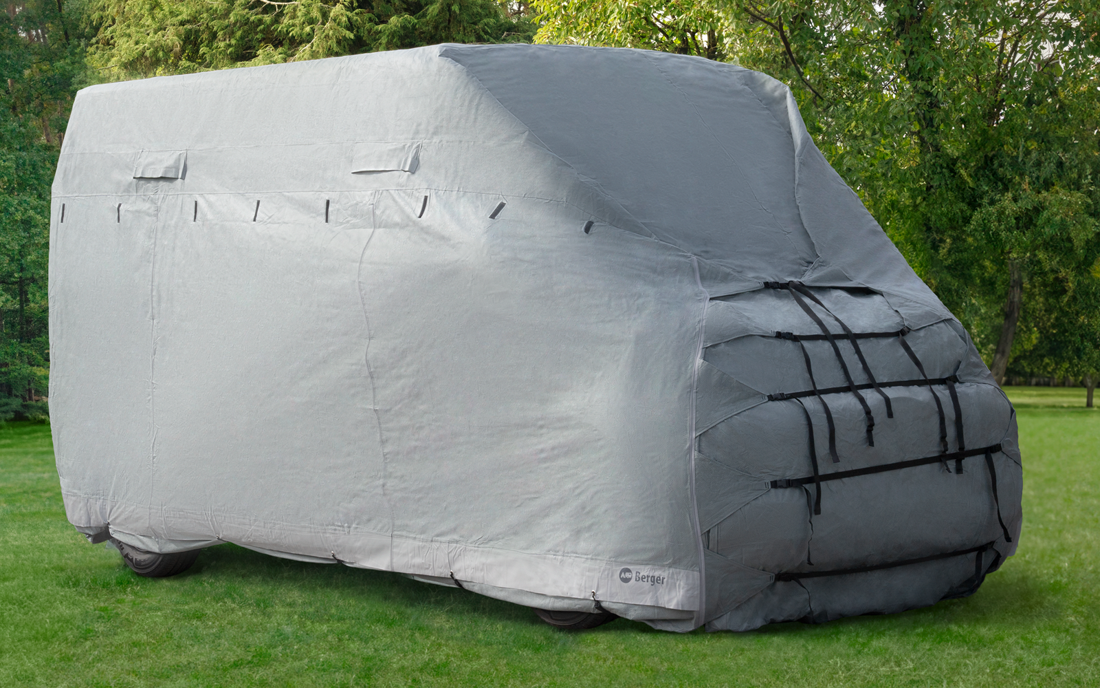 Graue Abdeckung bedeckt ein Fahrzeug auf grünem Rasen vor Bäumen