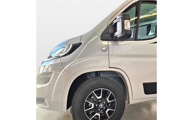 Vorderer rechter Teil eines weißen Fahrzeugs mit Scheinwerfer, Außenspiegel, Fenster und Reifen