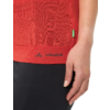Bas d'un t‑shirt rouge avec logo noir VAUDE à l'ourlet, petite étiquette latérale verte, main droite sur la hanche, pantalon noir