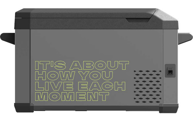 Graues rechteckiges Gerät mit Deckel und seitlichen Griffen, Lüftungsschlitzen rechts, kleinem Display und großem Schriftzug 'IT'S ABOUT HOW YOU LIVE EACH MOMENT' auf der Vorderseite
