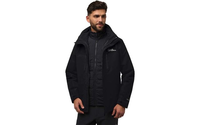 Homme aux cheveux courts foncés et barbe portant une veste à capuche noire par‑dessus une doudoune matelassée sur fond blanc