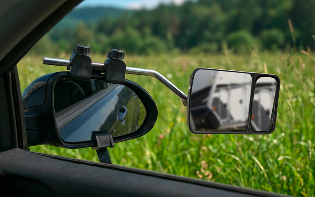 Rétroviseur extérieur d'une voiture avec vue sur une route de gravier et un champ vert en arrière-plan