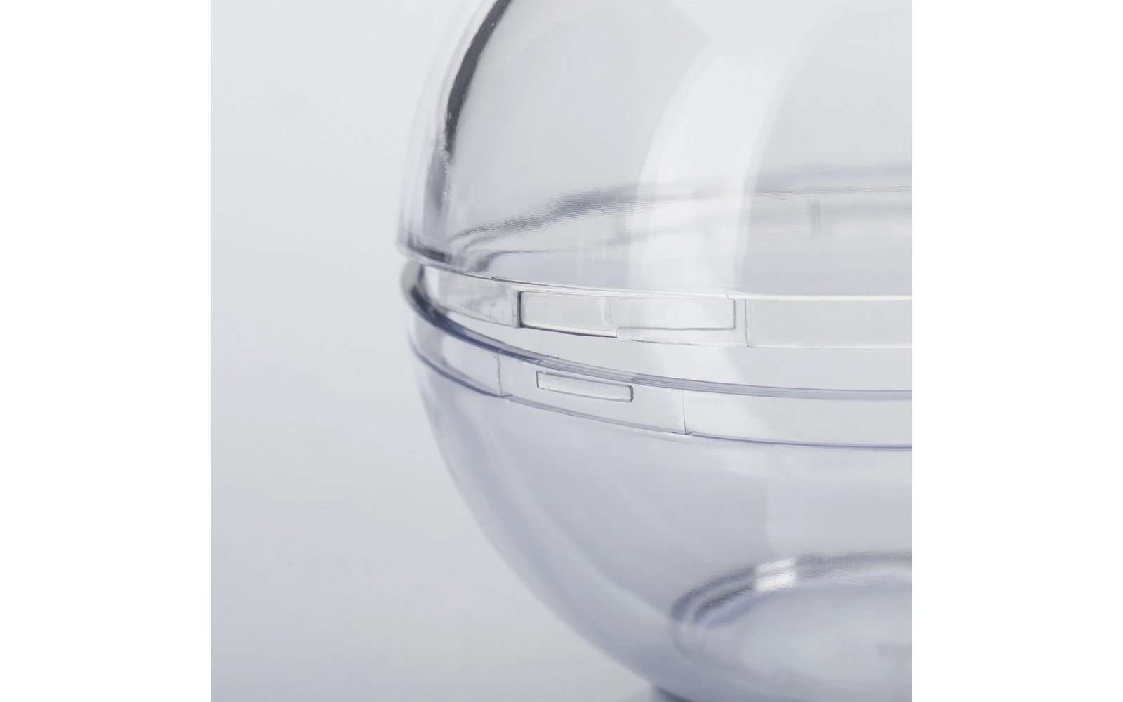 Gros plan d'une sphère transparente en plastique avec une ligne de joint et des fermoirs à clip sur fond clair