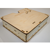 Flat square wooden box of light plywood with slots, round holes and visible interlocking joints at the edges
