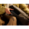 Eine Person zieht einen Reißverschluss an einer schwarzen Tasche zu