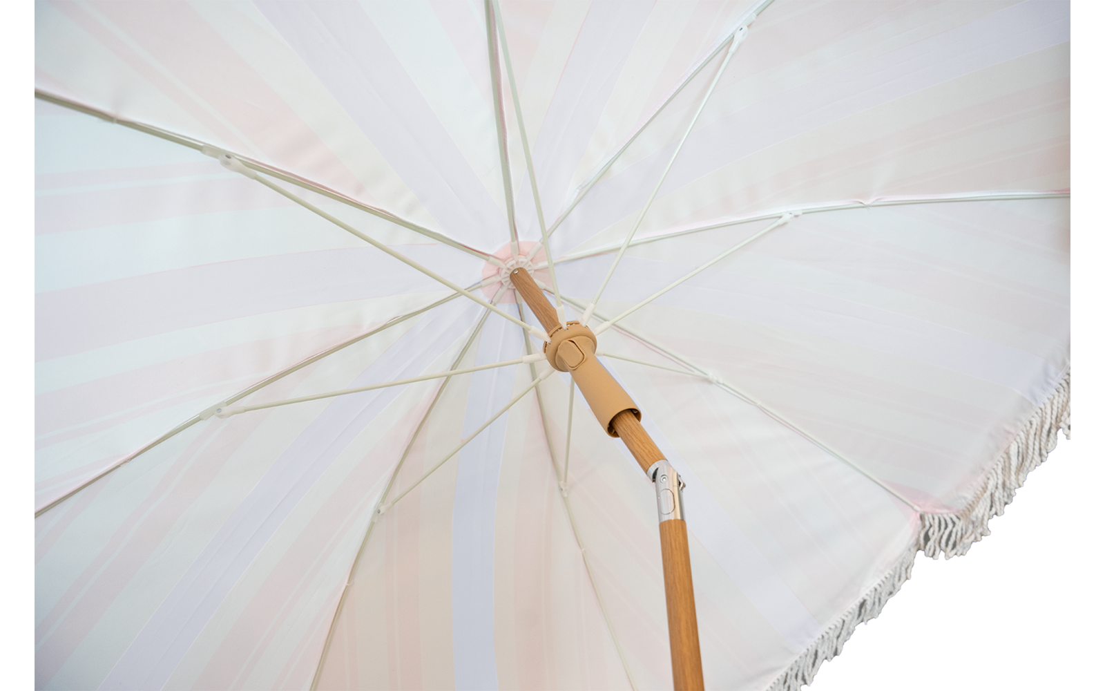 Unterseite eines pastellgestreiften Sonnenschirms mit Holzstange und Metallstreben