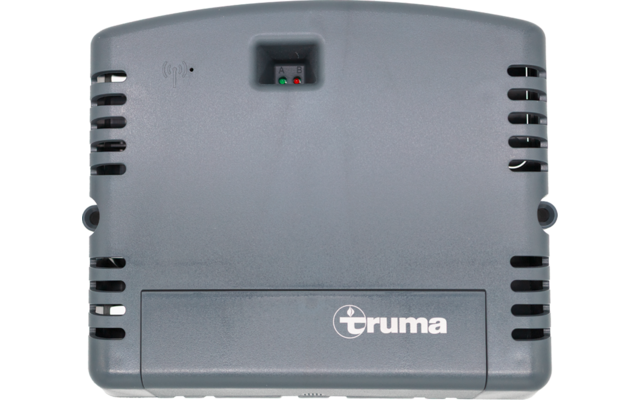Carcasa de plástico gris rectangular con logotipo 'truma', rejillas de ventilación y pequeña ventana con LED rojo y verde