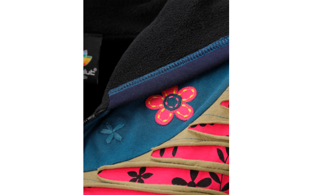 Gros plan d'un vêtement en polaire noir avec fermeture éclair, doublure bleue avec une fleur brodée rose et jaune et bandes beiges laissant apparaître un tissu rose à motif floral noir