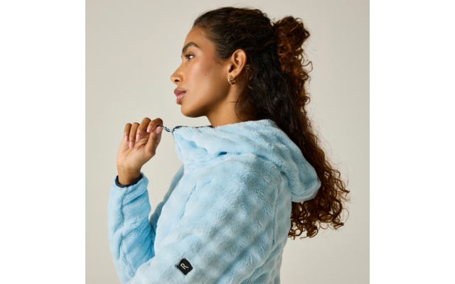 Persona de perfil con chaqueta con capucha azul claro de felpa, tira de un cordón