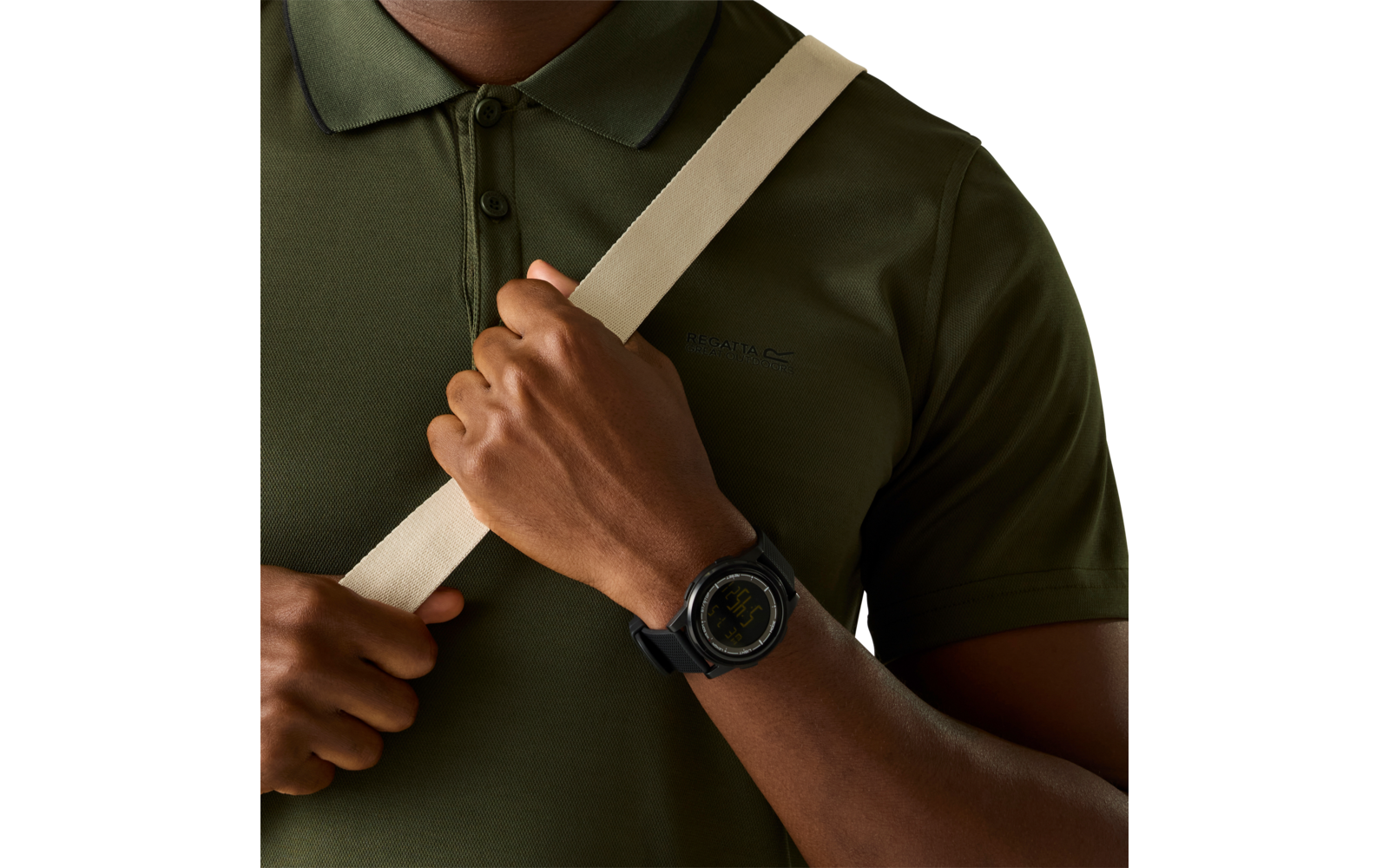 Bei­ge­schnittener Oberkörper einer Person in olivgrünem Poloshirt, ein beiger Riemen verläuft diagonal über die Brust, eine Hand hält den Riemen; am Handgelenk eine schwarze, runde Smartwatch