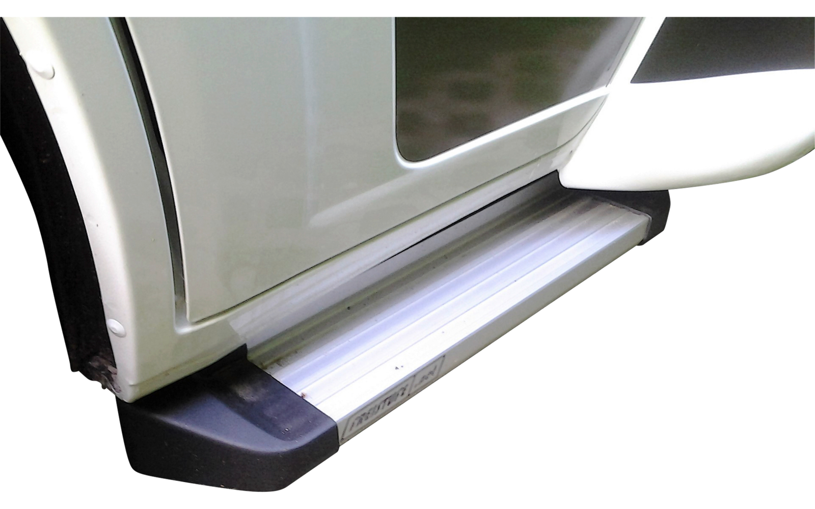 Marchepied replié sur un véhicule blanc garé sur un sol pavé avec de l'herbe