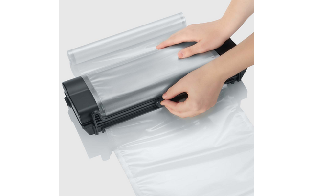 Twee handen voeren een transparante plastic zak door een zwart sluitingsapparaat