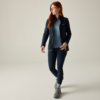Persona con capelli lunghi rossi che indossa una giacca blu scuro, maglietta blu, leggings blu scuro e scarpe da trekking grigie, in piedi su sfondo chiaro, guarda a destra