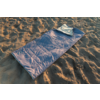 Sac de couchage bleu sur sol sablonneux, en haut un tissu plié, sable avec creux et ombres