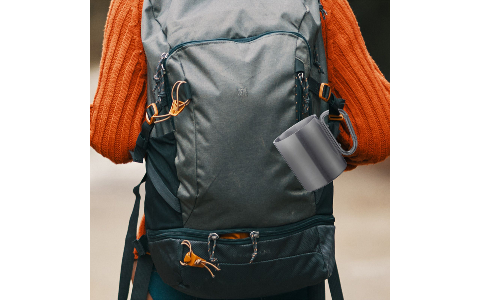 Rear view of a person in an orange knit sweater with a dark green backpack and a gray mug hanging from it