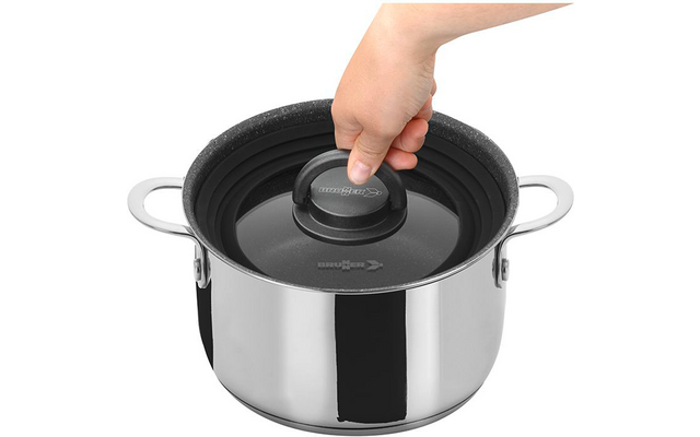Main saisissant le bouton d'un couvercle en verre sur une casserole en acier inoxydable avec deux poignées