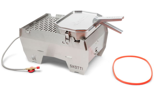 Grill en acier inoxydable sur quatre petits pieds, plaque de cuisson amovible avec poignée, tuyau de gaz flexible avec raccord métallique et joint orange détaché à côté