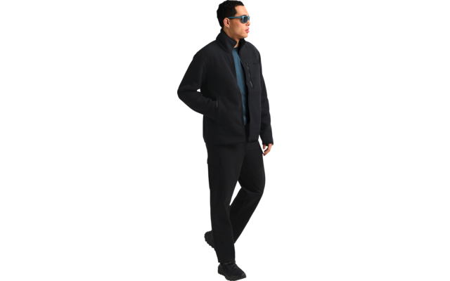 Ein Mann in schwarzem Mantel und dunkler Brille geht nach rechts