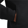 Eine Hand steckt in der Hosentasche einer schwarzen Jacke