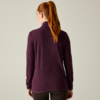 Vista posteriore di una persona con una coda di cavallo rossa che indossa una maglia viola a maniche lunghe e pantaloni scuri su sfondo chiaro