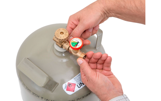 Deux mains tournent un détendeur sur une bouteille de gaz grise avec un autocollant d'avertissement