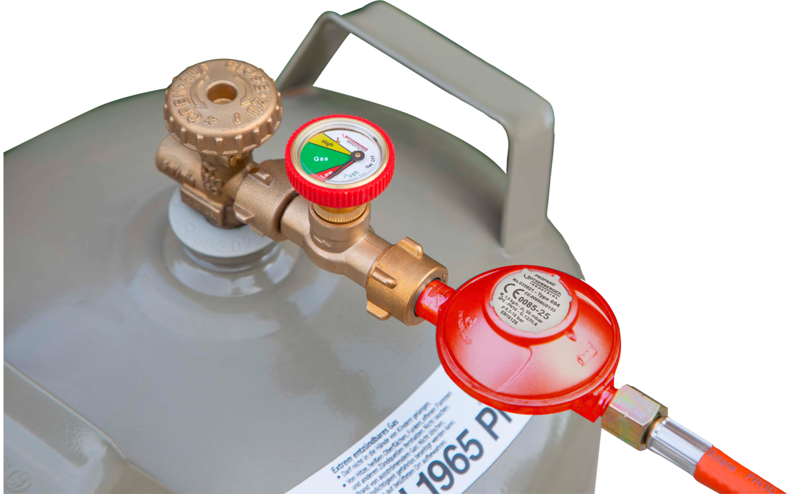 Bouteille de gaz grise avec poignée, robinet en laiton, manomètre et détendeur rouge relié à un tuyau orange ; feuillage vert flou en arrière-plan