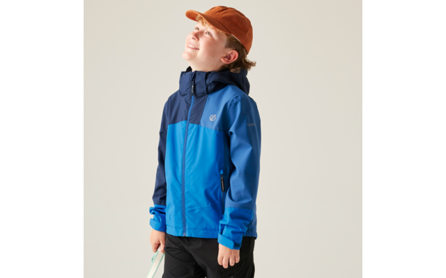 Kind in blau-dunkler Jacke mit Kapuze und orangefarbener Kappe, hält ein hellgrünes Objekt, blickt nach oben vor hellem Hintergrund