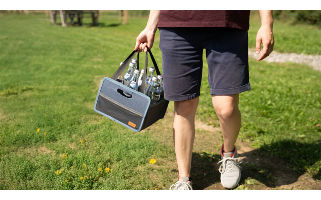 Personne tenant une petite enceinte à la main, chemin de promenade en zone verte