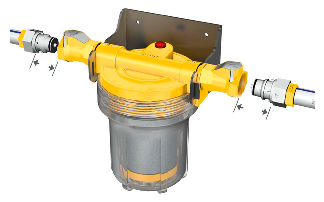 Gelbes Gehäuse mit klarem, zylindrischem Behälter darunter, roter Knopf oben, Metallhalterung im Hintergrund, links und rechts Rohranschlüsse mit Schnellkupplungen und schwarzen Pfeilmarkierungen