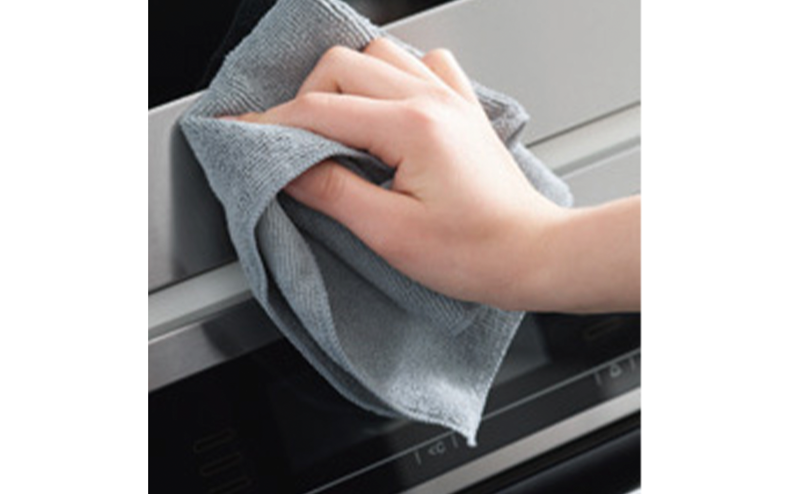 Hand mit grauem Tuch wischt metallische Vorderseite eines Küchengeräts