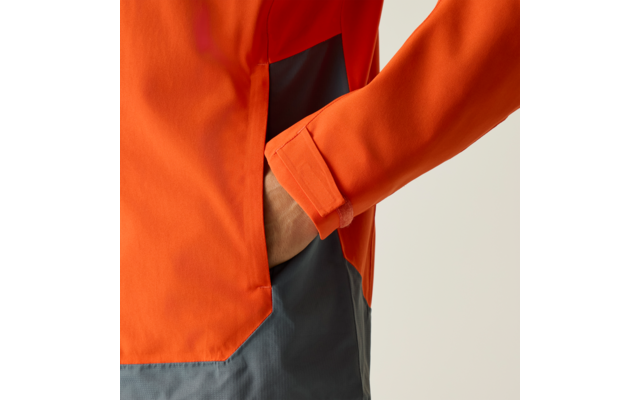 Nahaufnahme eines orangefarbenen Jackenärmels mit einer Hand in einer seitlichen Tasche, darunter ist ein graues Kleidungsstück sichtbar