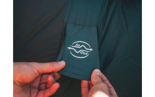 Hand hält ein abnehmbares Etikett mit einem weißen Logo auf dunkelblauem Stoff